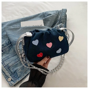 Detail of denim bucket bag with colorful heart patches and silver metal ring handle
