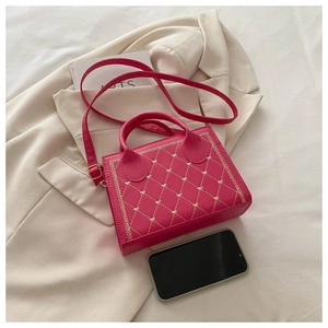 Detail of hot pink quilted square handbag with heart embroidery and gold hardware