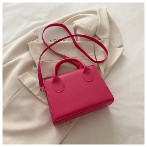 Detail of rose red rectangular crossbody bag on white blazer with artsy book