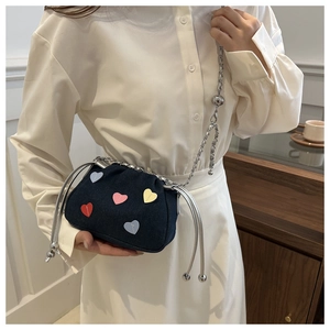 Close-up of blue denim crossbody bag with colorful heart patches and silver chain