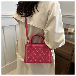 Detail of rose red crossbody bag featuring gold heart embroidery and quilted texture