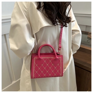 Detail of pink leather handbag featuring heart embroidery and quilted textures