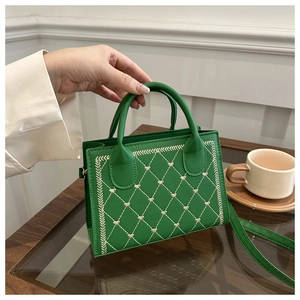 Detail of green square bag with heart embroidery and quilted pattern details
