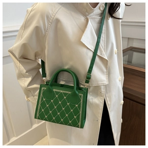 Detail of green square bag with rhombic pattern and gold heart embroidery accents