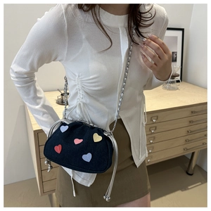Mini navy denim bucket bag with colorful leather hearts and silver chain on model