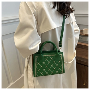 Close-up of green crossbody bag with heart-shaped embroidery on quilted faux leather
