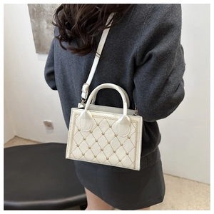 Rear view of model wearing white quilted crossbody bag with golden heart details