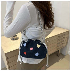 Detail of dark blue denim cloud bag with colorful heart patches and silver chain strap