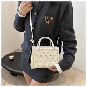 Close-up of white quilted crossbody bag with gold heart stitching and thin shoulder strap