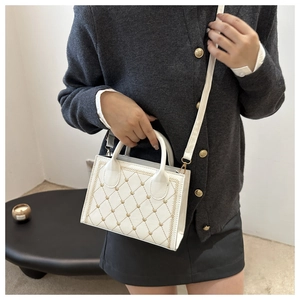 Detailed view of white quilted crossbody bag with golden heart embroidery and model styling