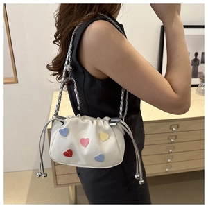Detail of off-white cloud bucket bag with colorful heart patches and silver chain strap