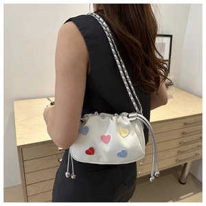 Chic cream canvas bucket bag with colorful heart patches and silver chain strap details