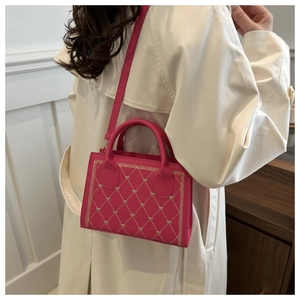 Quilted heart embroidery handbag in magenta finish styled on a beige trench coat