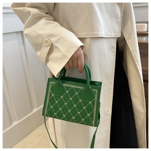 Detail of green crossbody bag featuring heart-shaped quilted stitching and top handle