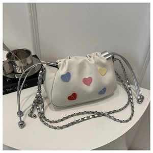 Detail of cream canvas cloud bag with colorful heart patches and silver chain strap