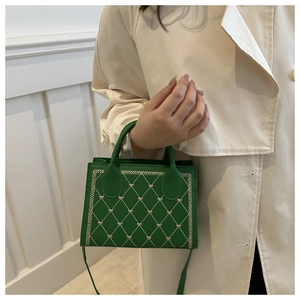Close-up of dark green quilted mini tote bag with heart embroidery and top handles