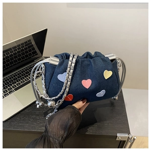 Detail view of denim cloud bag with colorful heart patches and silver metal chain strap