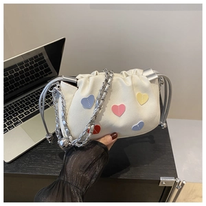 Close-up of beige drawstring bucket bag with colorful heart patches and silver chain