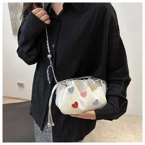 Side view of white cloud crossbody bag with colorful heart patches and silver chain