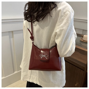 Détail du sac porté épaule bordeaux avec nœud argenté et bandoulière à nœud élégant