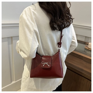 Détail du sac seau bordeaux avec nœud argenté et bandoulière à nœud décoratif