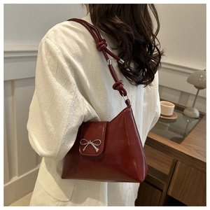 Détail du sac à bandoulière rouge brillant avec boucle nœud argenté et bandoulière