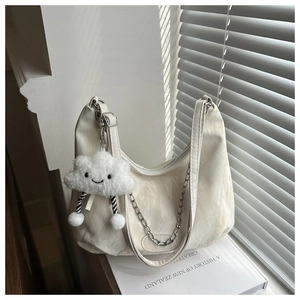 Detail of cream-colored hobo bag with wrinkled texture, silver chain, and cloud charm