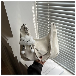 Close-up of white hobo bag with chain strap, pleated texture, and plush cloud charm