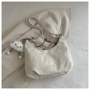 Detail of cream pleated crossbody bag with metal chain and plush cloud charm accessory