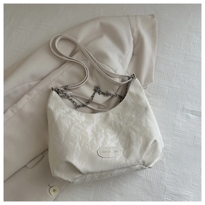 Detail of cream white shoulder bag with marble texture and silver chain strap
