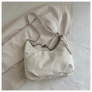 Detail of an ivory hobo bag with marble texture, adjustable strap and decorative metal chain