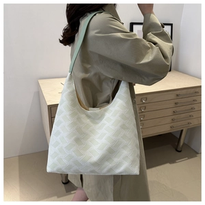 Detailed side view of woven shoulder bag with white and green textured geometric pattern