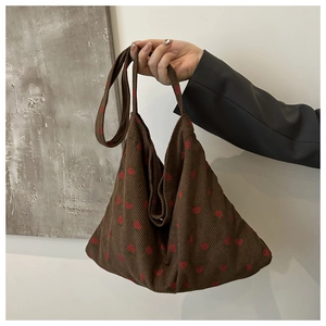 Close-up of strawberry embroidery on brown corduroy tote bag with wide shoulder strap