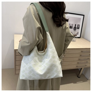 Detail of white woven tote bag featuring light green leather shoulder straps in use