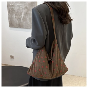 Detail of strawberry print on brown corduroy hobo bag showing texture and wide strap