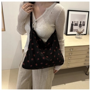 Detailed view of large black corduroy tote bag with red strawberry pattern and hobo style