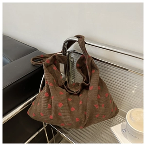 Detailed texture of brown corduroy hobo bag with red strawberry embroidery patterns