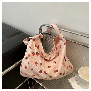 Close-up of pink corduroy tote bag featuring red strawberry patterns and soft texture