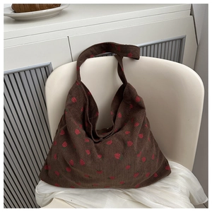 Close-up of strawberry print on dark brown corduroy tote bag featuring a hobo shoulder strap