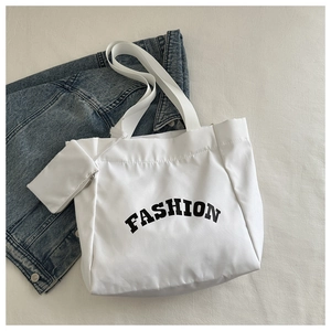 Détail du sac fourre-tout en toile blanche avec imprimé FASHION et petite pochette zippée