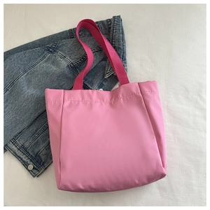 Détail du sac fourre-tout rose avec larges bretelles rose rouge et veste en jean