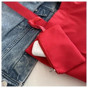 Détail d'un grand sac fourre-tout rouge avec pochette assortie sur fond de veste en jean