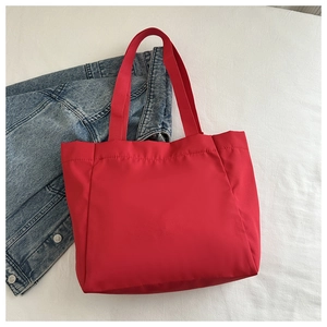 Détail d'un grand sac cabas en toile rouge avec de larges anses près d'une veste en jean