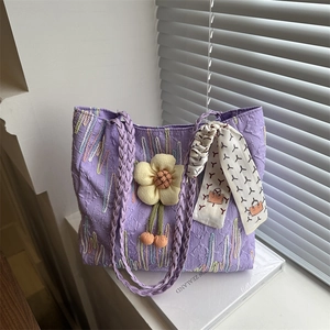 Purple embossed tote bag with floral charm and silk scarf on a sunny window sill