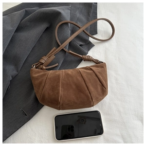 Detailed top view of a brown suede crescent bag with pleated design and knot strap