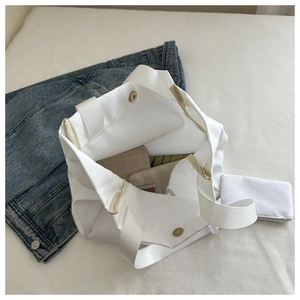 Détail d'un grand cabas en toile blanche avec bouton pression et pochette zippée assortie