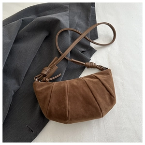 Detail of vintage brown suede croissant bag with pleated texture and knot shoulder strap