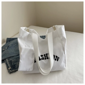 Détail d'un grand sac fourre-tout blanc en toile avec imprimé FASHION et pochette