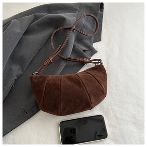 Detail view of coffee suede crescent bag with pleated stitching and slender strap