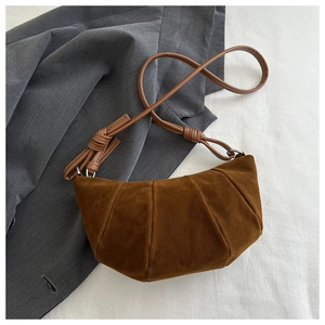 Detailed texture of brown suede crescent bag with vertical stitching and knotted shoulder strap